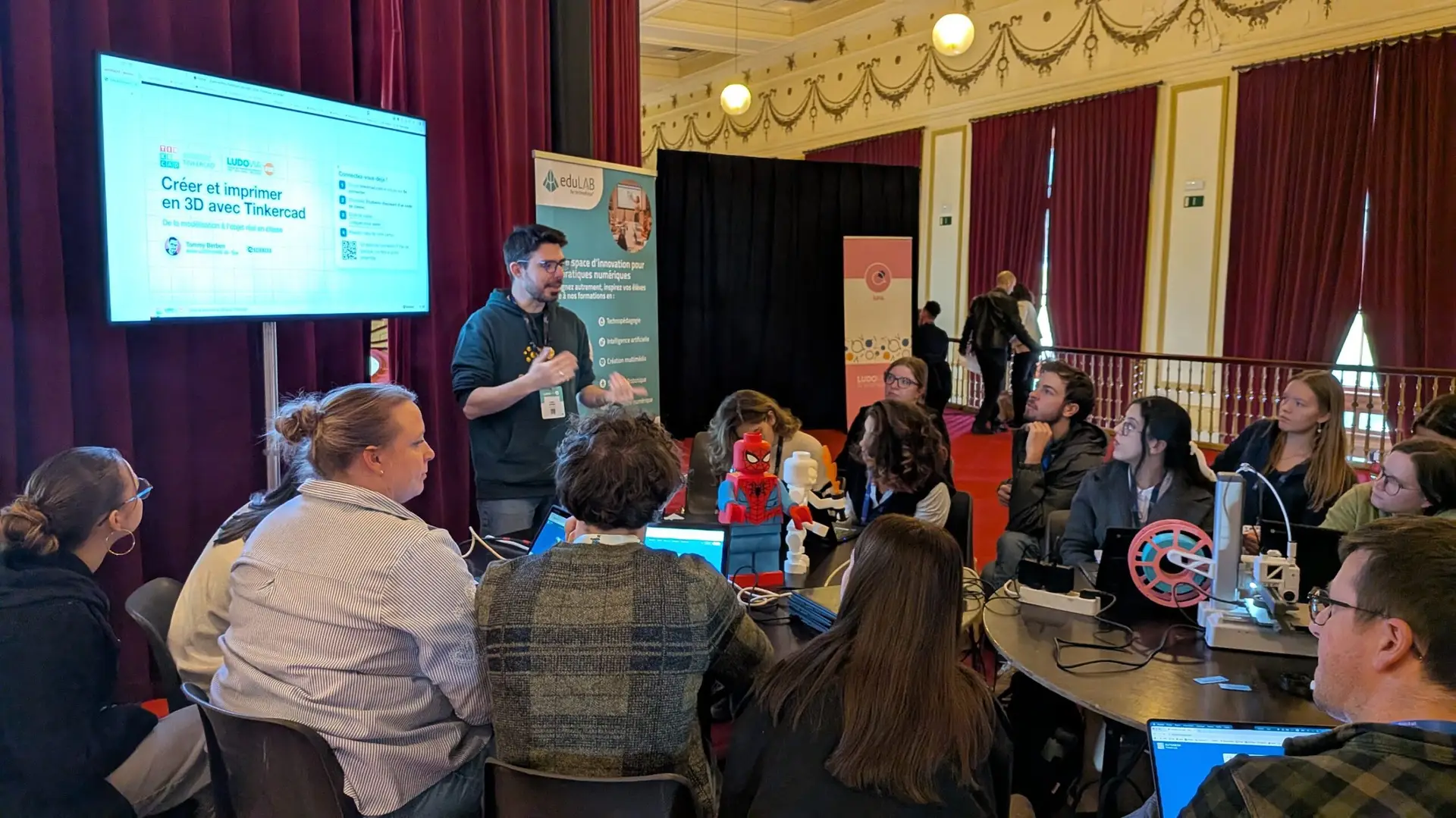 Tommy Berben anime un atelier « Créer et imprimer en 3D avec Tinkercad » devant des enseignants réunis autour de tables, avec ordinateurs et imprimante 3D